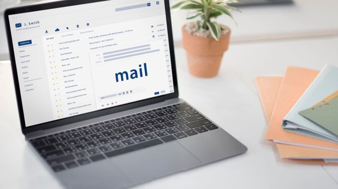 an opened laptop with email word on it, a flowers and notebooks on the table